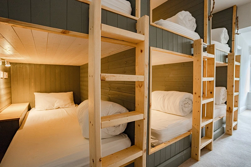 Cosy bunk beds with wooden ladders in a bright hostel room, ideal for budget travellers and group stays.