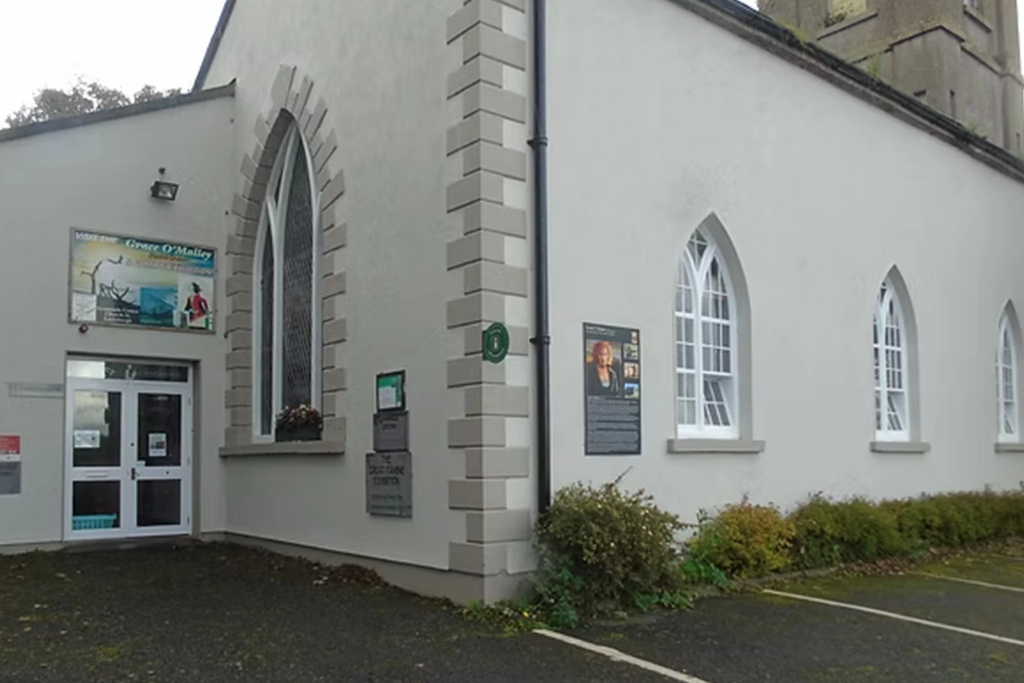 Historic Irish building with arched windows, signage, and entrance displaying a Grace O'Malley exhibition poster.